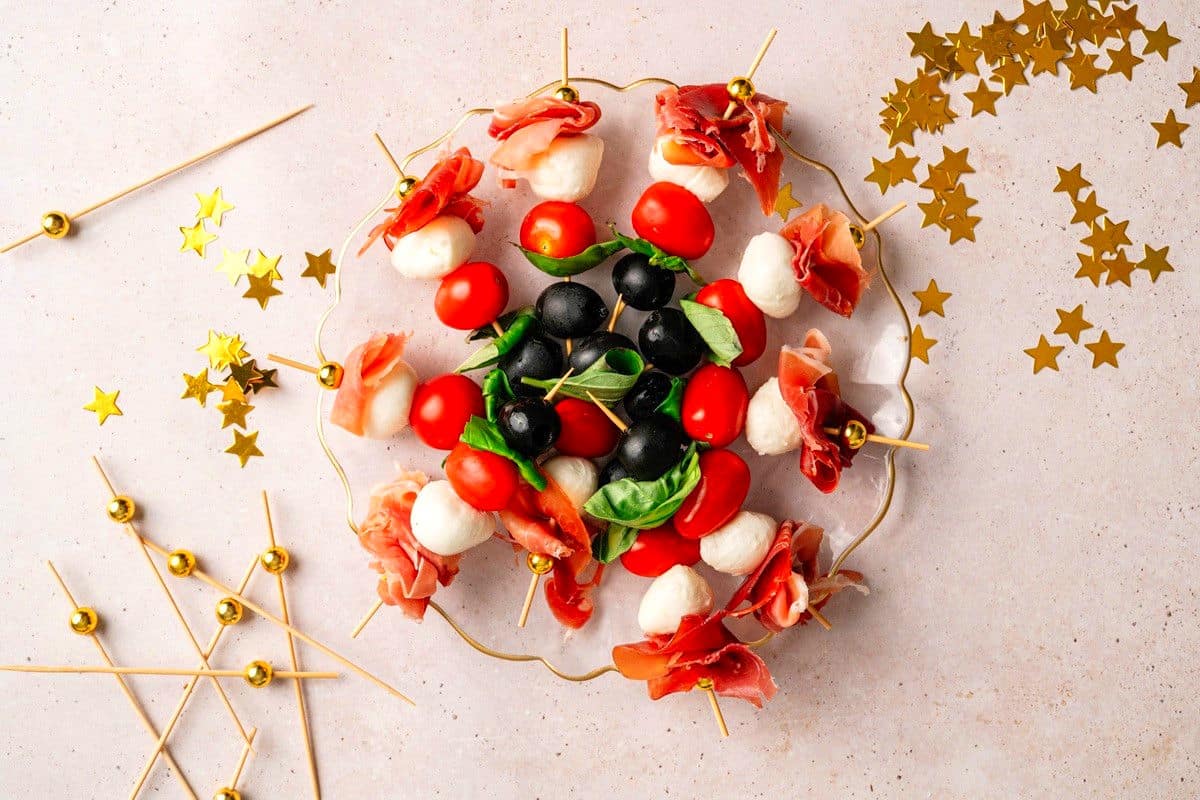 Mini caprese skewers on a plate with new year's eve decorations.