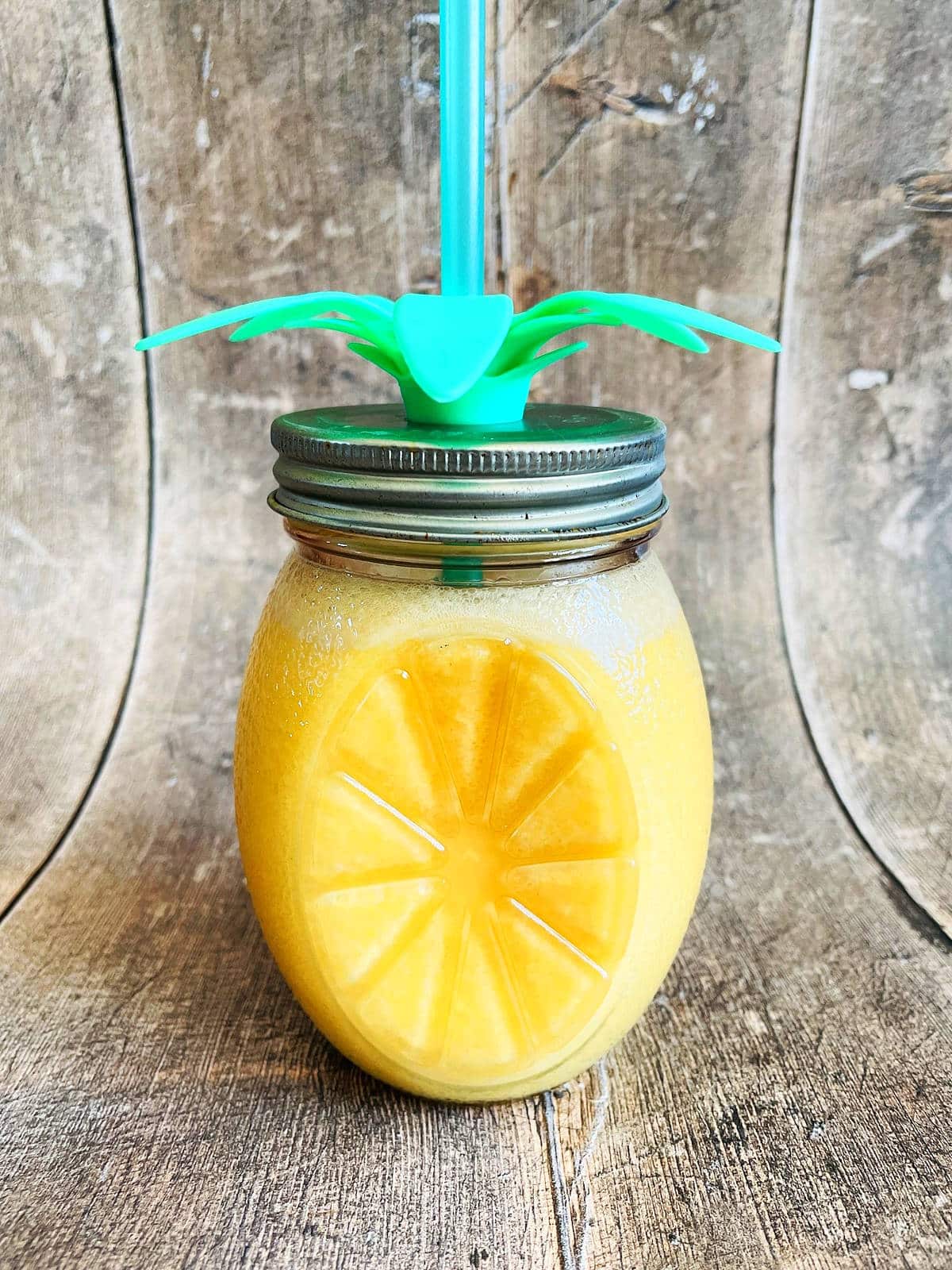 Orange Julius in glass with lid and straw.