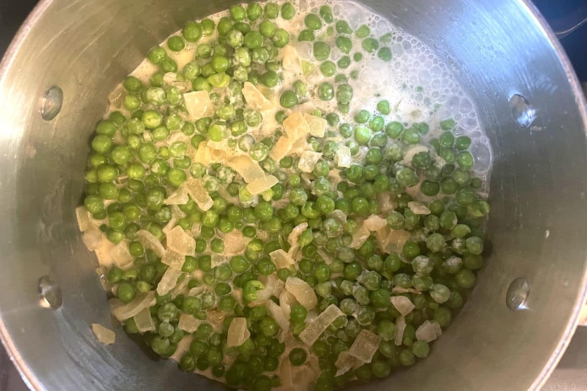 Green peas with cream and onions in saucepan.