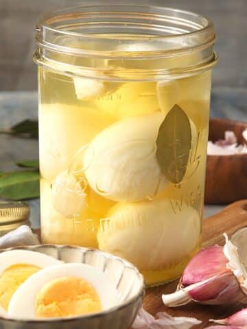 Pickled eggs in jar and sliced open in a bowl.