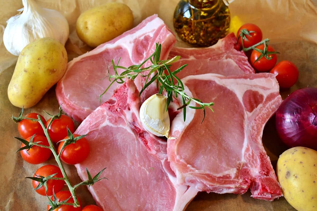 Raw pork chops surrounded by vegetables.