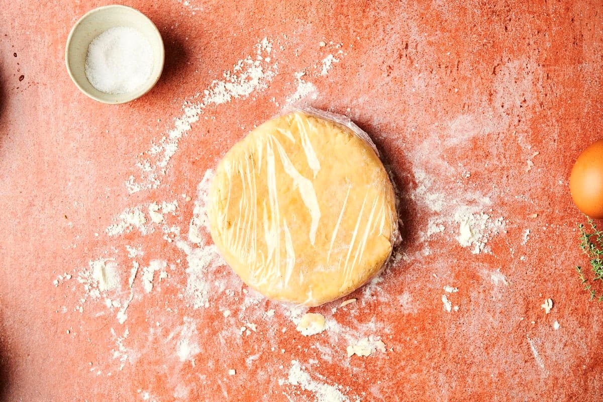 Galette dough flattened and covered in plastic wrap.