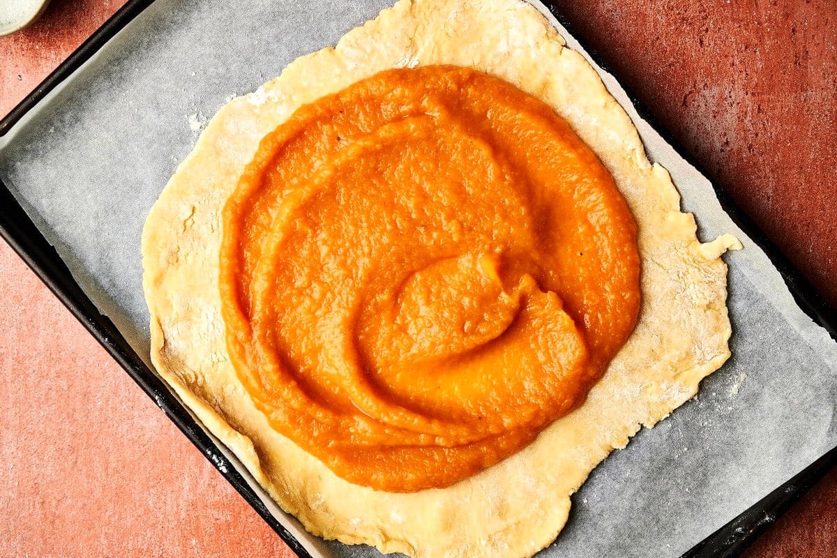 Pumpkin galette dough and filling on baking sheet.