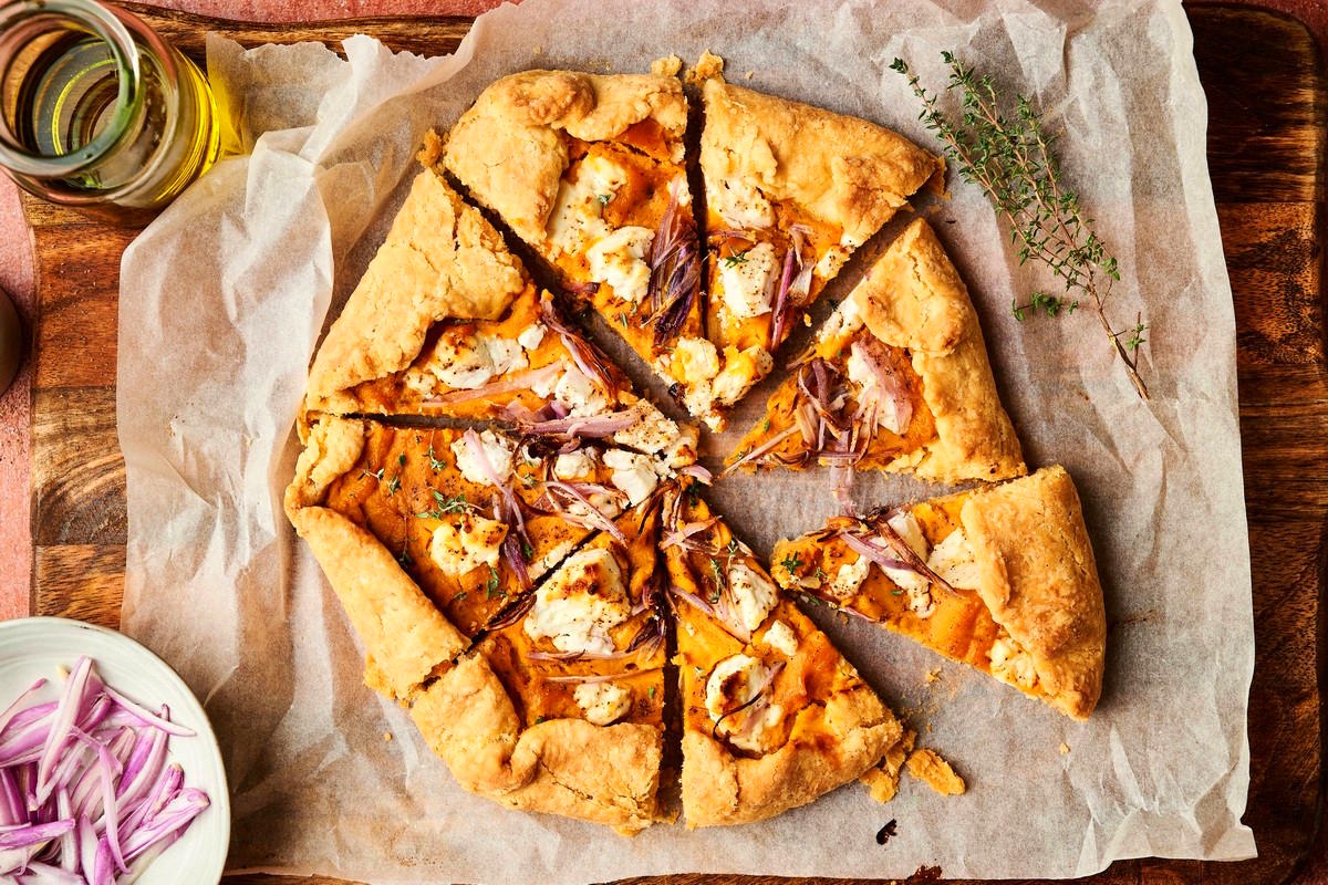Baked and sliced pumpkin galette on wooden board.