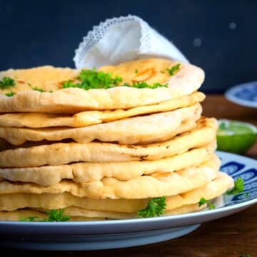 Pumpkin naan breads stacked on a plate.