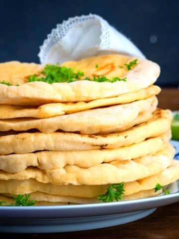 Pumpkin naan breads stacked on a plate.