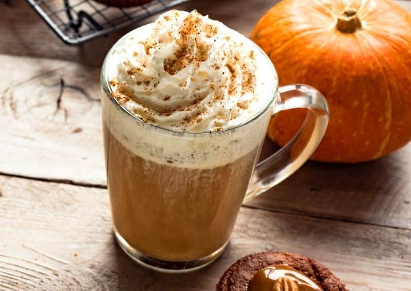 Pumpkin spice latte with a pumpkin in the background.