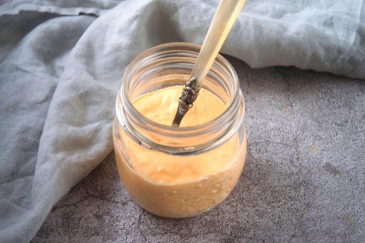 Kimchi mayo in small jar with spoon.