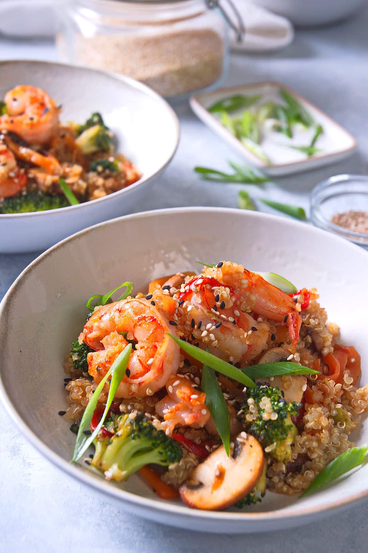 Quinoa stir fry with shrimp and veggies in white bowl.