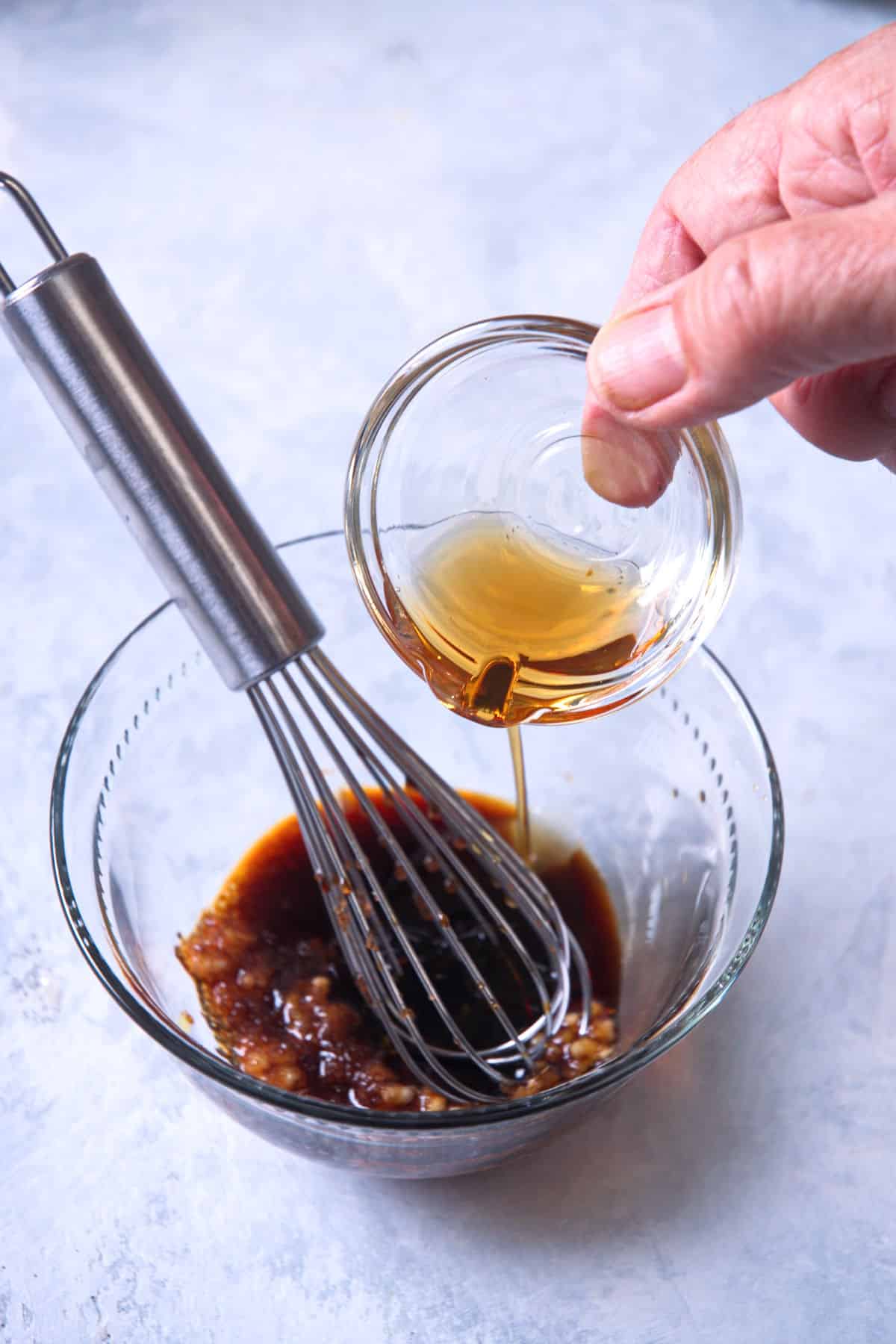 Quinoa stir fry sauce in bowl with whisk.