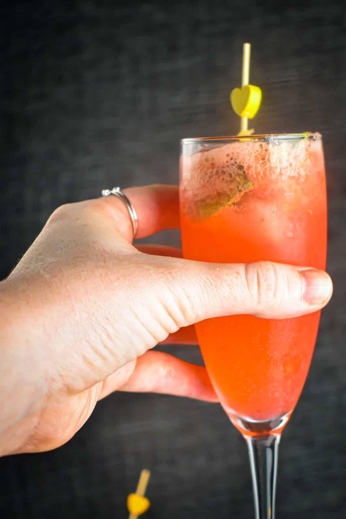 A woman's hand holding a raspberry twist cocktail.