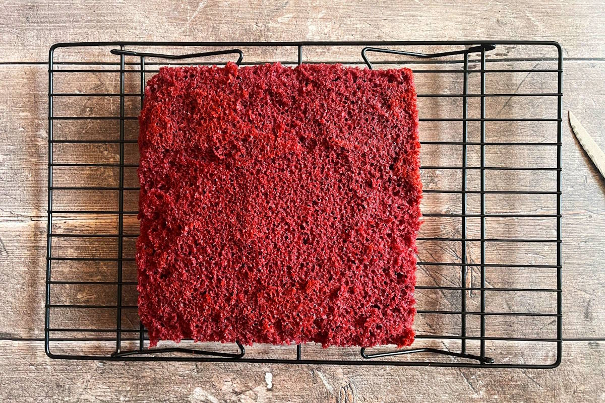 Red velvet cake trimmed on baking rack.
