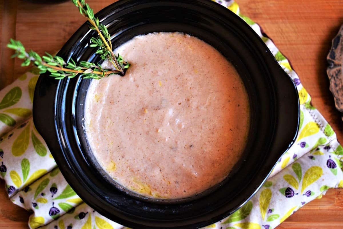 Red wine cheese dip in mini slow cooker with fresh thyme.