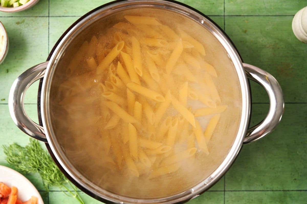 Penne pasta cooking in pot.