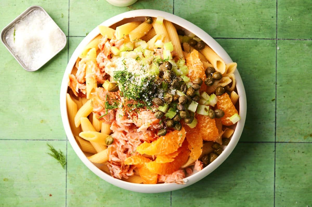 Smoked salmon pasta salad ingredients in white bowl.