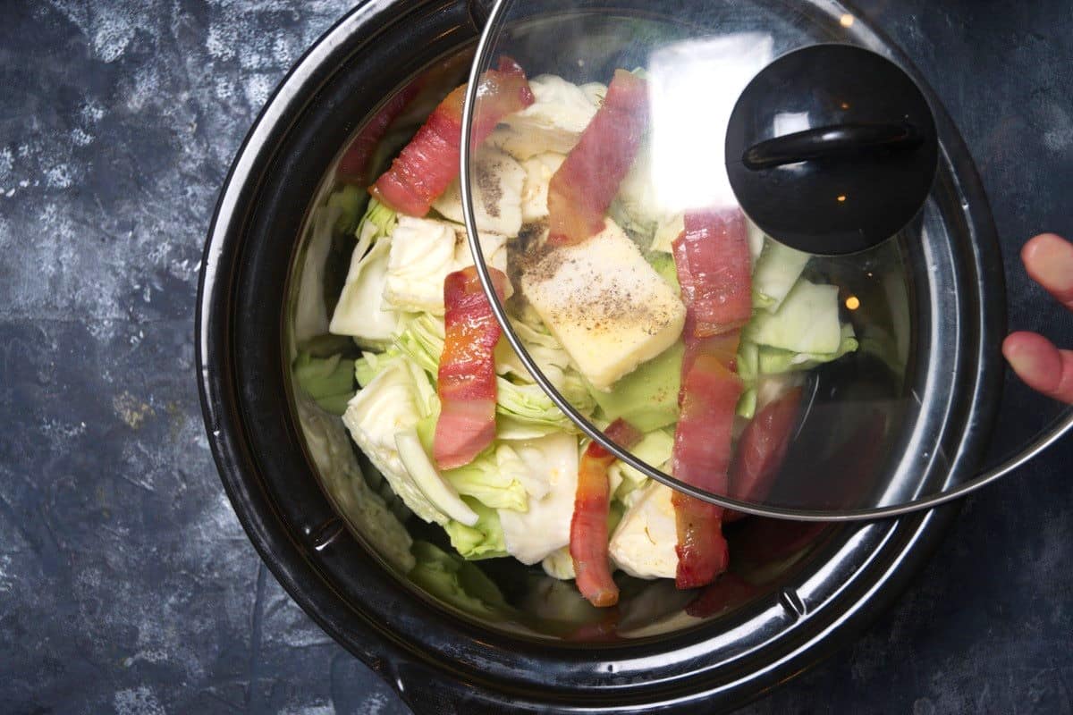 Cabbage and bacon in slow cooker with lid.