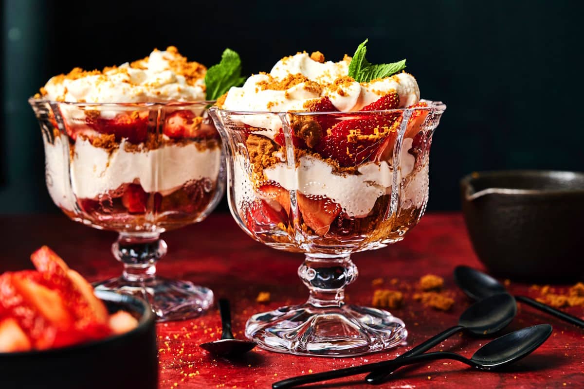 Strawberry parfaits in glasses with black spoons on the side.