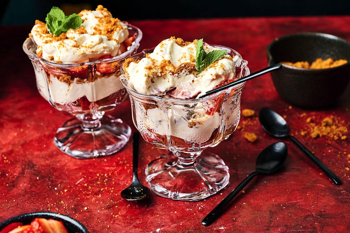 Strawberry parfaits in glasses with black spoon.
