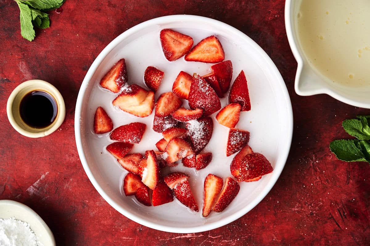 Sliced strawberries, sugar and orange liqueur in dish.