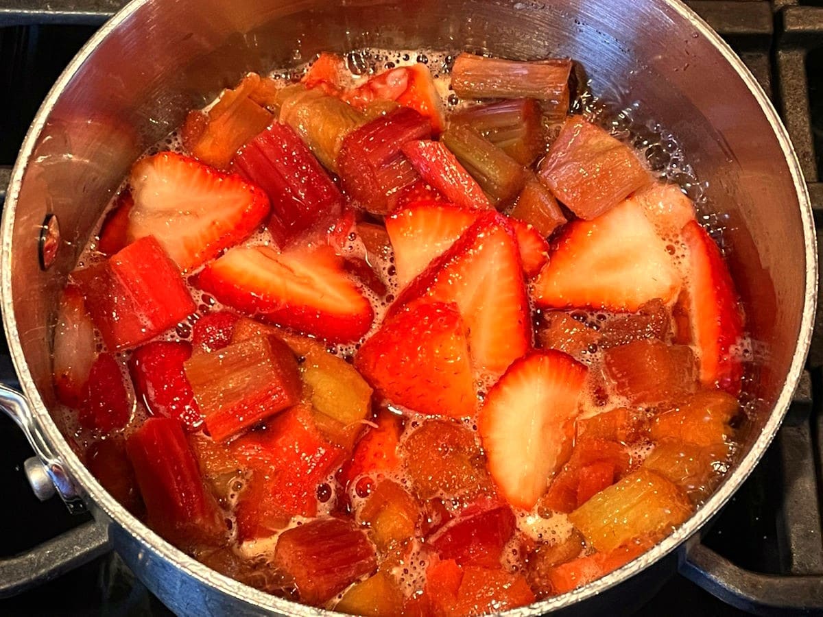 Strawberry rhubarb sauce simmering in saucepan.