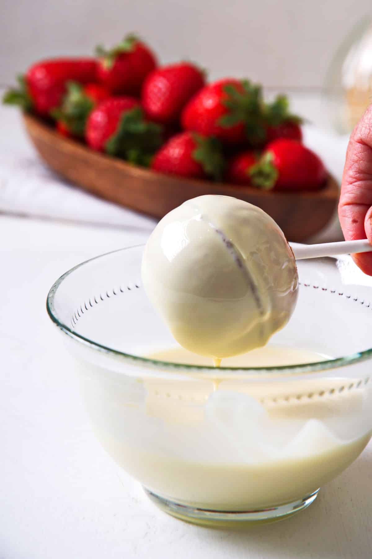 Strawberry cake pop dipped into white chocolate coating.