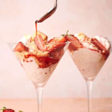 Strawberry shortcake ice cream in martini glasses with syrup pouring out of spoon.