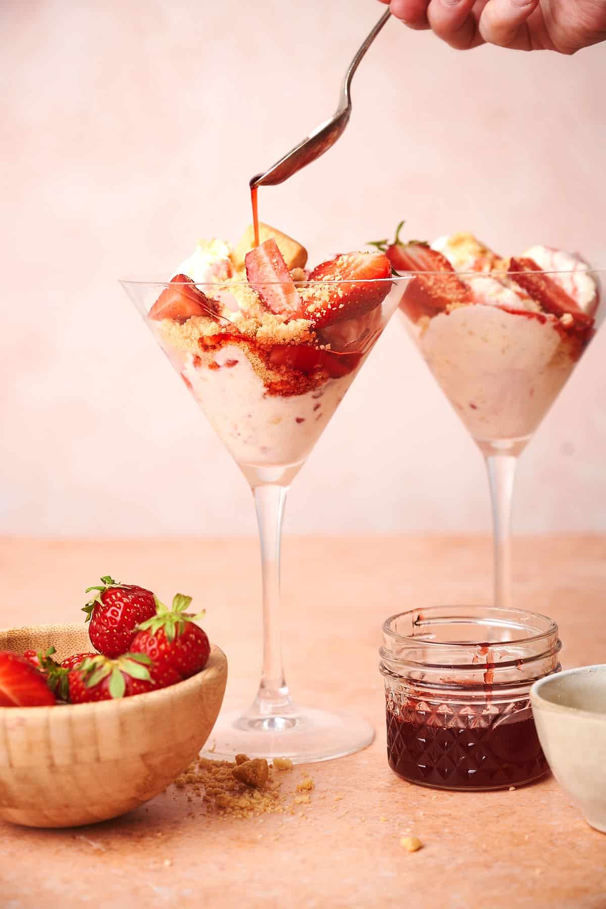 Strawberry shortcake ice cream in martini glasses with fresh strawberries in a bowl.