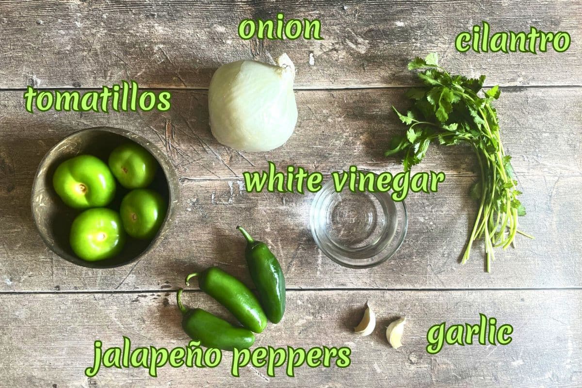 Tomatillo hot sauce ingredients labeled on wooden background.