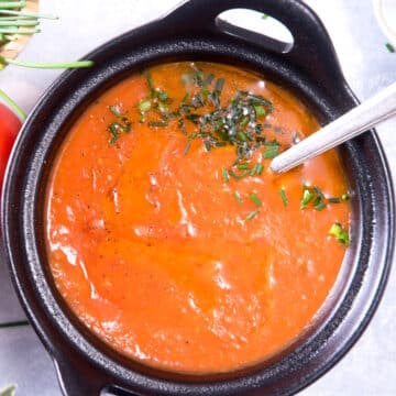 Tomato gravy in cast iron bowl with spoon.