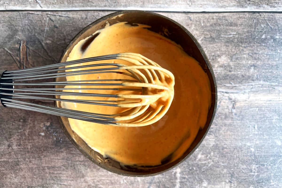 Sriracha mayo in bowl with whisk.