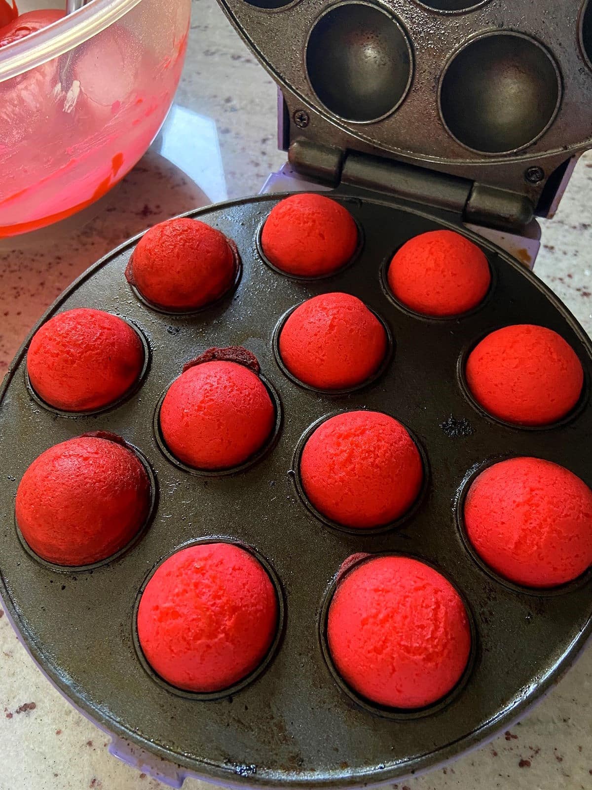 Red cake balls in cake pop maker.