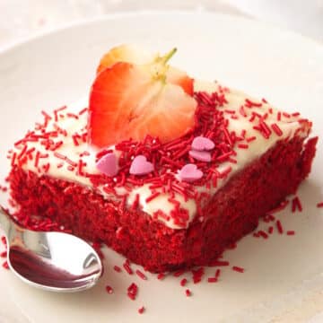 Valentine's Day cake slice on white plate with fresh strawberry slices.