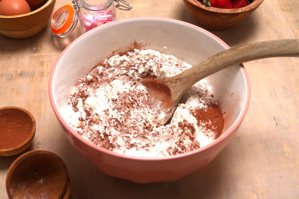 Cocoa powder and flour in bowl with wooden spoon.