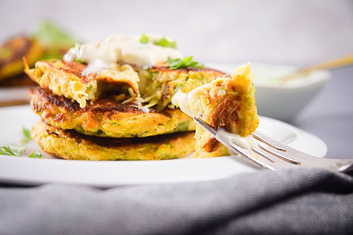 Zucchini crab cakes stack on plate and on a fork.